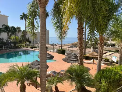a pool with umbrellas and chairs and palm trees at Lagos Vila Mós 59 in Lagos