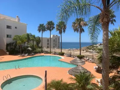 a swimming pool with palm trees and the ocean at Lagos Beach 59A in Lagos