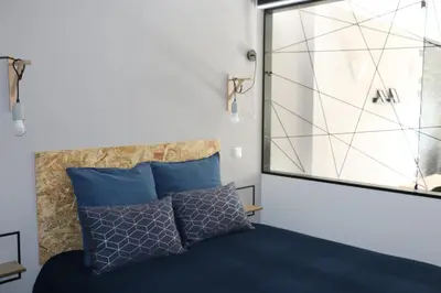 a bedroom with a bed with blue pillows and a window at Lagos Beach 59A in Lagos