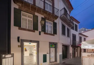 a white building with green shutters on a street at OurMadeira - Heart of Old Town II in Funchal