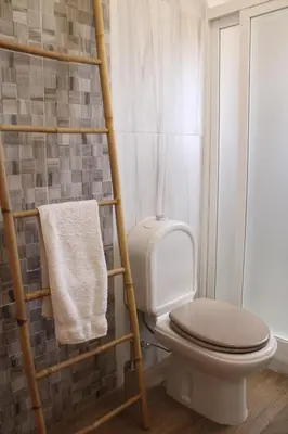 a bathroom with a toilet and a towel rack at Abrigo das Nortadas in Vila do Bispo