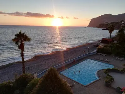 a swimming pool on the beach at sunset at By the Beach & Pool Apartment in Funchal