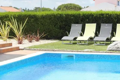 a swimming pool with lounge chairs next to a hedge at VILLA ANDORINHA with Private Pool in a quiet area in Aljezur