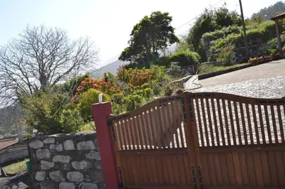 a wooden gate in front of a stone wall at Recantos do Castanheiro in Porto Moniz