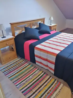 a bedroom with a bed and a rug at Recantos do Castanheiro in Porto Moniz