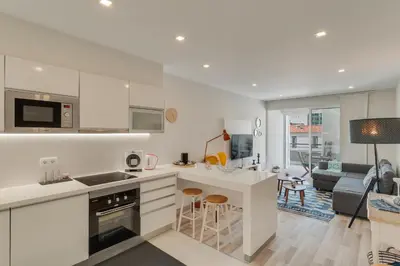 a kitchen with white cabinets and a living room at Braganza apartment in Funchal