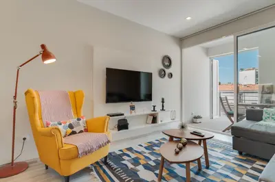 a living room with a yellow chair and a tv at Braganza apartment in Funchal