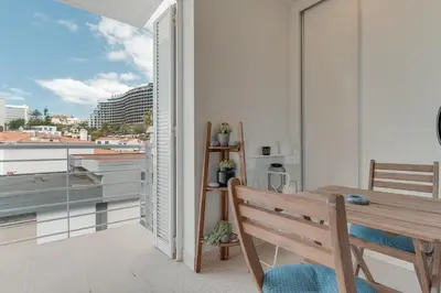 a balcony with a wooden table and a view of a city at Braganza apartment in Funchal