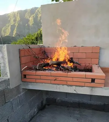 a fire in a brick fireplace with a mountain in the background at Casa do Vale in São Vicente