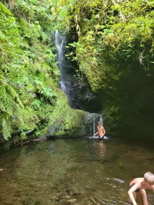 a man standing in a river in front of a waterfall at Casa do Vale in São Vicente