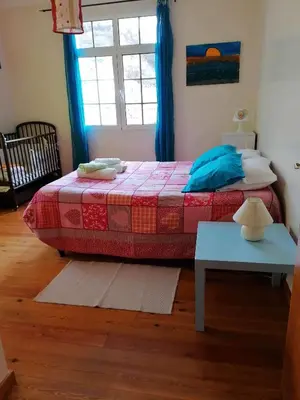 a bedroom with a bed with a table and a window at Casa do Vale in São Vicente