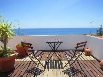 a balcony with two chairs and a table and the ocean at IM On Luz Arte in Luz