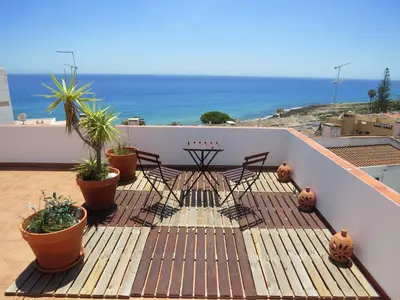 a balcony with chairs and potted plants and the ocean at IM On Luz Arte in Luz
