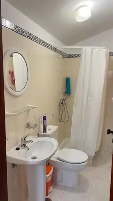 a bathroom with a sink and a toilet and a mirror at Apartamento Miradouro in Carrapateira