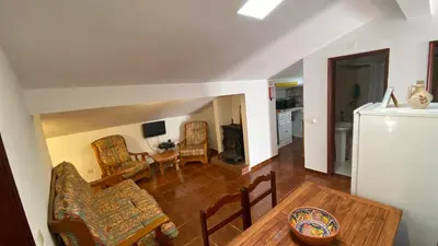 a living room with a table and chairs and a kitchen at Apartamento Miradouro in Carrapateira