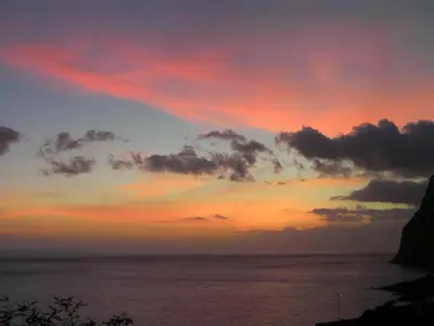 a sunset over a body of water with a cliff at The Best Atlantic Ocean View in Câmara de Lobos