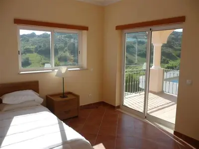 a bedroom with a bed and a view of a balcony at Lovely Burgau villa just 3 mins walk from beach in Budens