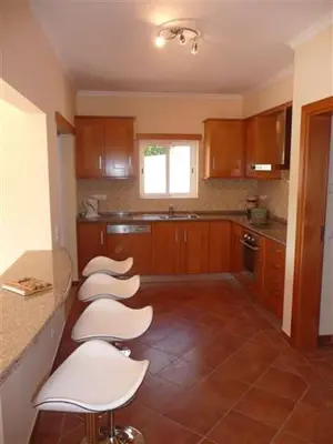 a kitchen with four white stools and a counter at Lovely Burgau villa just 3 mins walk from beach in Budens