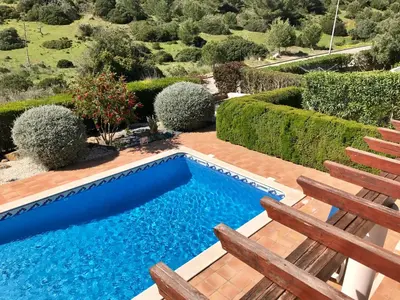 a swimming pool in the middle of a garden at Lovely Burgau villa just 3 mins walk from beach in Budens