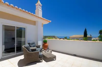 a patio with wicker furniture and a white wall at Villa Montanha, 4 Bedroom Villa, with swimming pool, loungers and alfresco dining, 10 min walk to the beautiful Praia da Luz Beach, Shops, Bars and Restaurants! in Luz