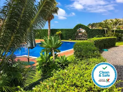 a resort with a swimming pool and palm trees at Casa Charmosa in Funchal