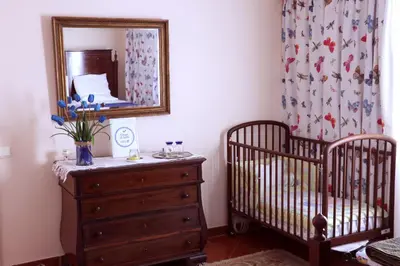 a bedroom with two cribs and a dresser and a mirror at Casa Charmosa in Funchal