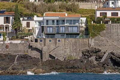 a house on a cliff next to the water at Beach House - By WeHost in Santa Cruz