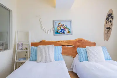 a bedroom with two beds with blue and white pillows at Beach House - By WeHost in Santa Cruz