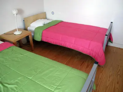two beds in a room with a table and a lamp at Azores Youth Hostels - Santa Maria in Vila do Porto