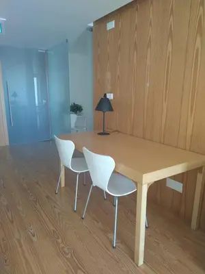 a wooden table with white chairs and a lamp at Azores Youth Hostels - Santa Maria in Vila do Porto