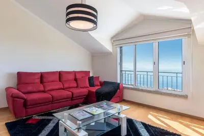 a living room with a red couch and a large window at Savana Apartment By Atlantic Holiday in Nogueira