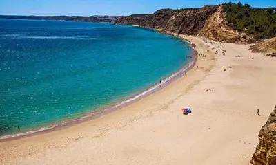 a beach with a group of people in the water at Cantinho do Burgau in Burgau