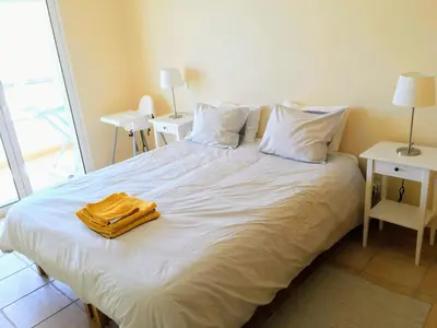 a large white bed with a yellow robe on it at Varandas - Arrifana, com piscina, junto à praia in Praia da Arrifana