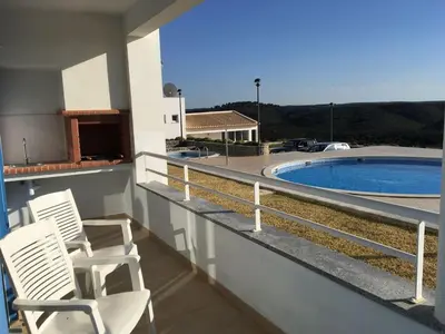 a balcony with two chairs and a swimming pool at Varandas - Arrifana, com piscina, junto à praia in Praia da Arrifana