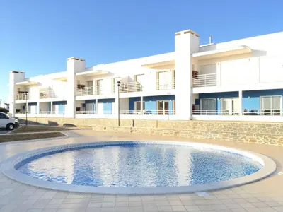 a building with a swimming pool in front of a building at Varandas - Arrifana, com piscina, junto à praia in Praia da Arrifana