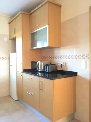 a kitchen with wooden cabinets and a black counter top at Varandas - Arrifana, com piscina, junto à praia in Praia da Arrifana