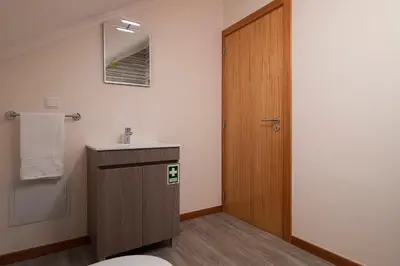 a bathroom with a sink and a wooden door at SEA VIEW LOFT MADEIRA in Ribeira Brava