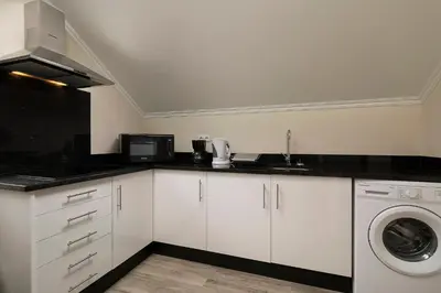 a kitchen with white cabinets and a washer and dryer at SEA VIEW LOFT MADEIRA in Ribeira Brava