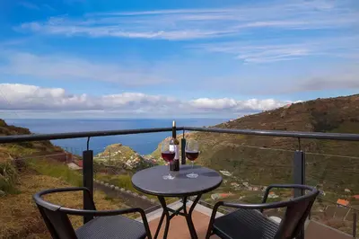 two glasses of wine sitting on a table on a balcony at SEA VIEW LOFT MADEIRA in Ribeira Brava