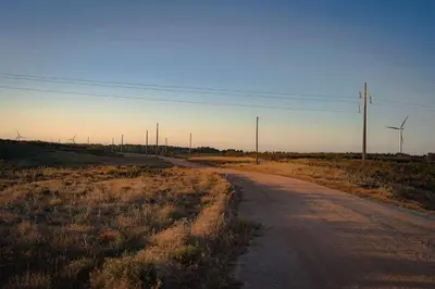an empty road in the middle of a field with wind turbines at Casa O Recanto in Raposeira