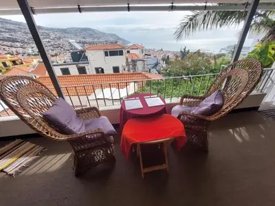 a balcony with a table and chairs and the ocean at Casa Pico Musica in Funchal