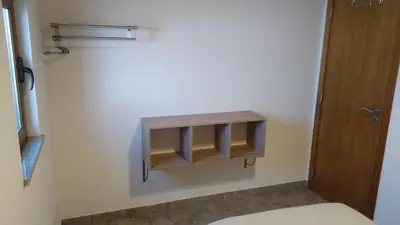a bathroom with a toilet and a shelf on the wall at O Nosso Lar in Lagos