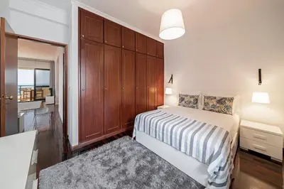 a bedroom with a bed and a wooden cabinet at Garajau II by An Island Apart in Caniço