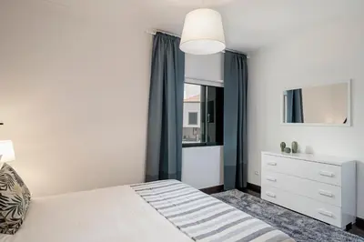 a bedroom with a white bed and a window at Garajau II by An Island Apart in Caniço