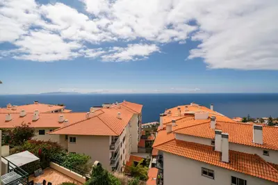 a view of roofs of buildings and the ocean at Garajau II by An Island Apart in Caniço