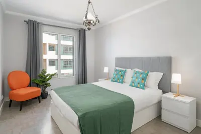 a white bedroom with a large bed and a chair at Promenade I by An Island Apart in Funchal