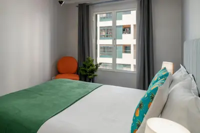 a bedroom with a bed with an orange chair and a window at Promenade I by An Island Apart in Funchal