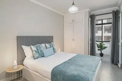 a white bedroom with a large bed with blue pillows at Promenade I by An Island Apart in Funchal