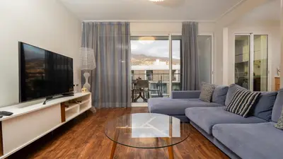 a living room with a blue couch and a tv at Gardenia Apartment by LovelyStay in Funchal
