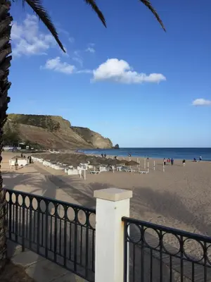 a beach with white chairs and people on the beach at ST JAMES in Luz
